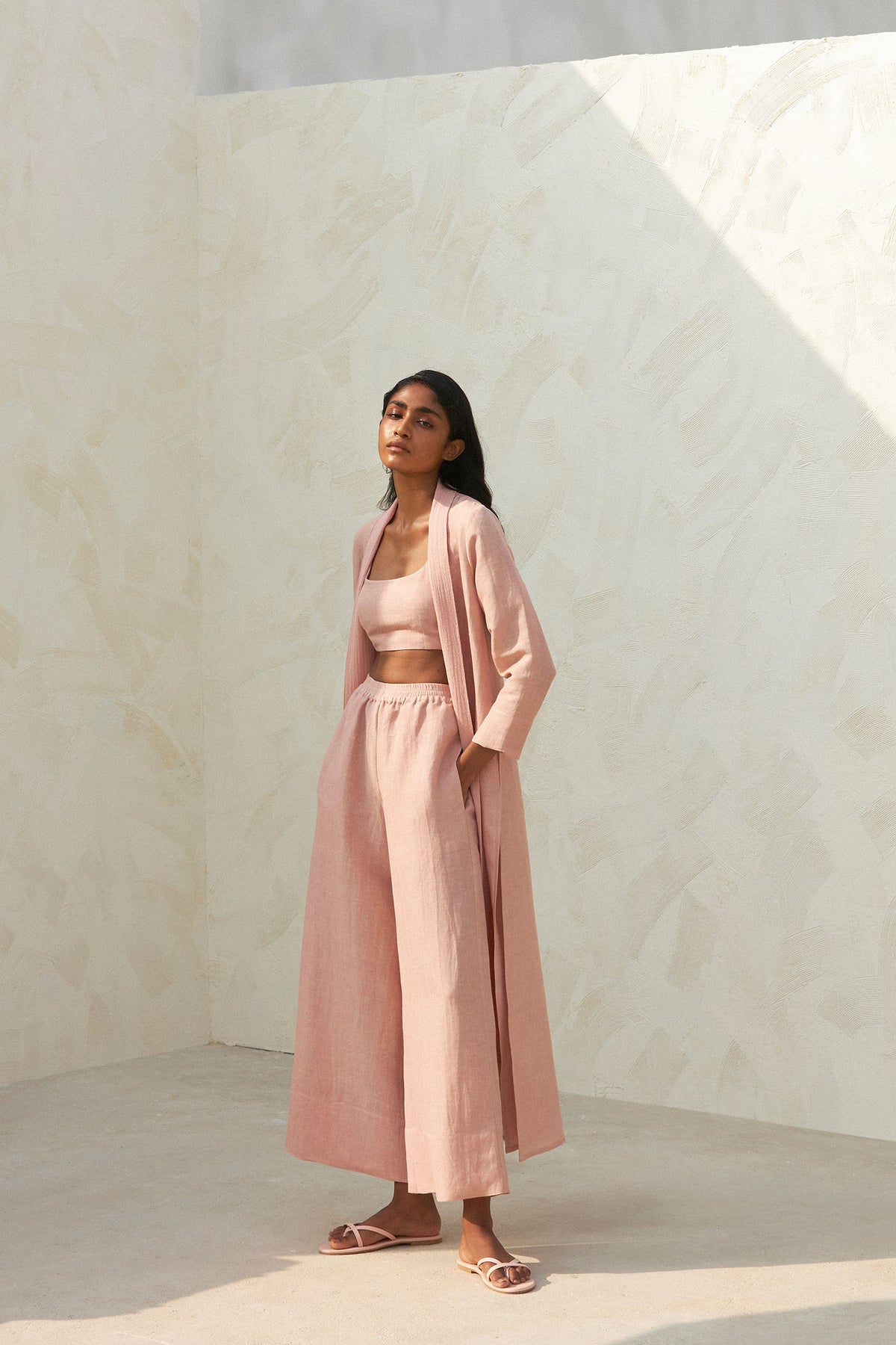 Woman wearing a pink crop top, cardigan and wide-leg trousers