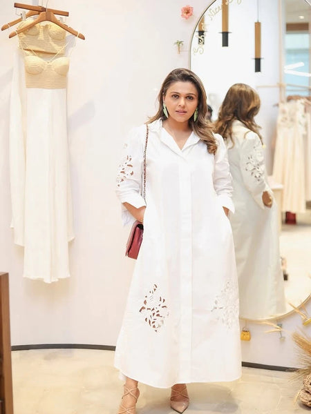 Woman wearing a white embroidered shirt dress in a boutique